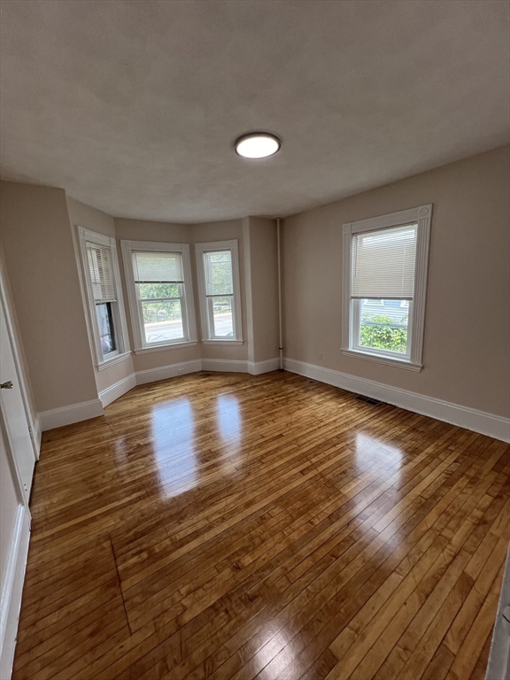 a view of empty room with window and wooden floor