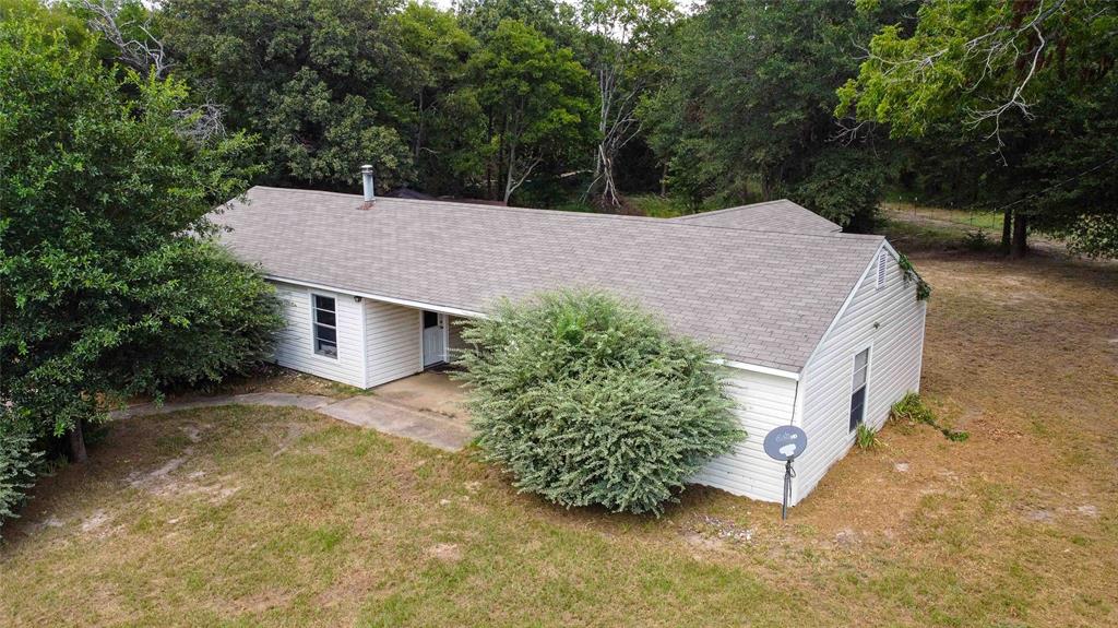 a aerial view of a house with yard and trees all around