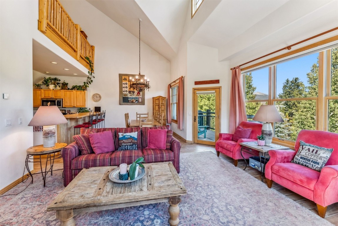 Living room featuring high vaulted ceiling, a wealth of natural light, and an inviting chandelier