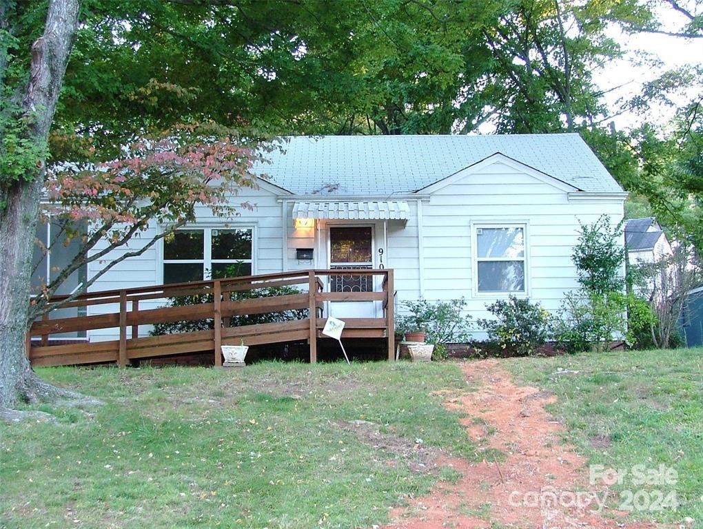 a backyard of a house with wooden fence and a large tree