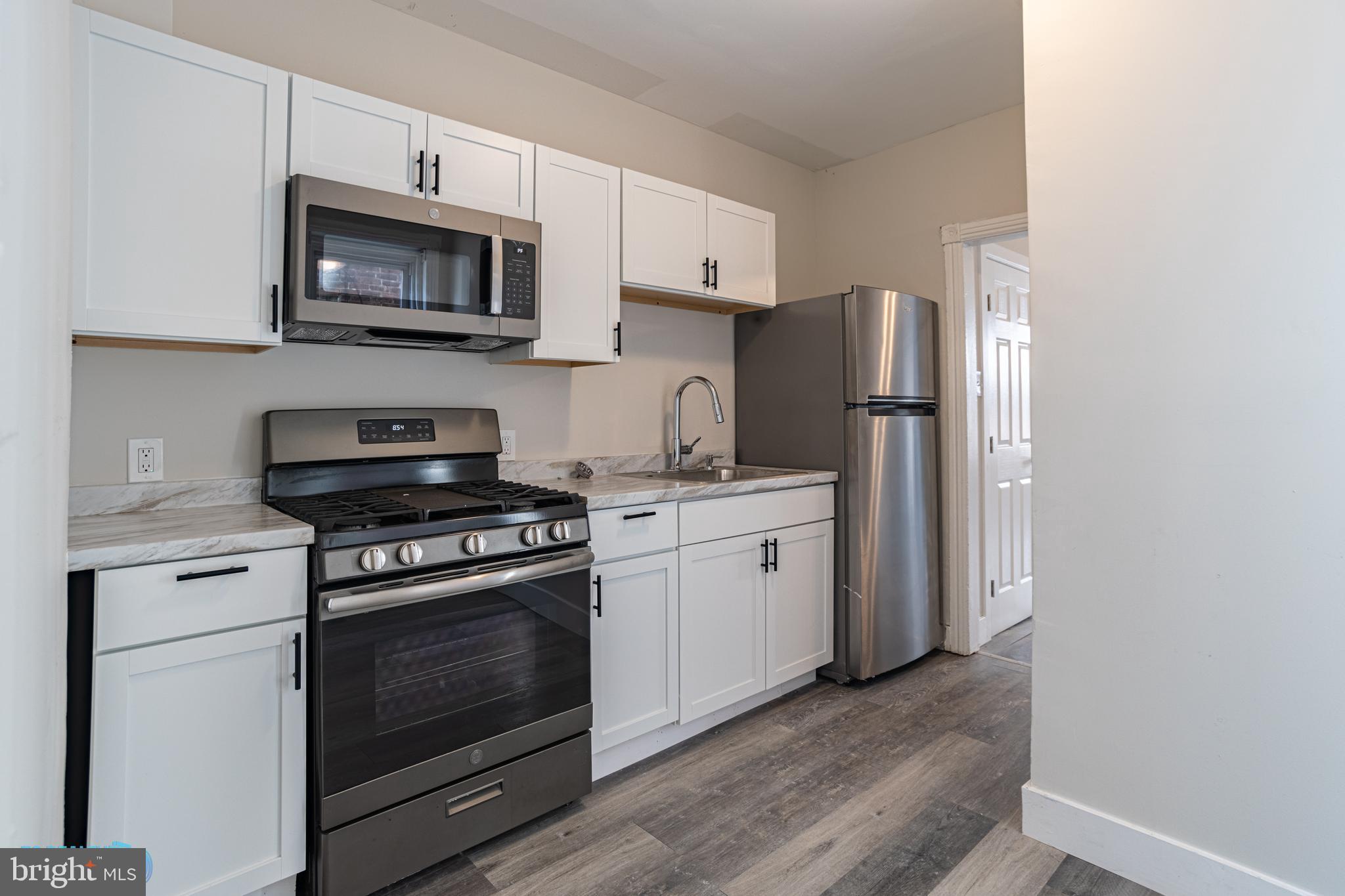 a kitchen with cabinets stainless steel appliances and wooden floor