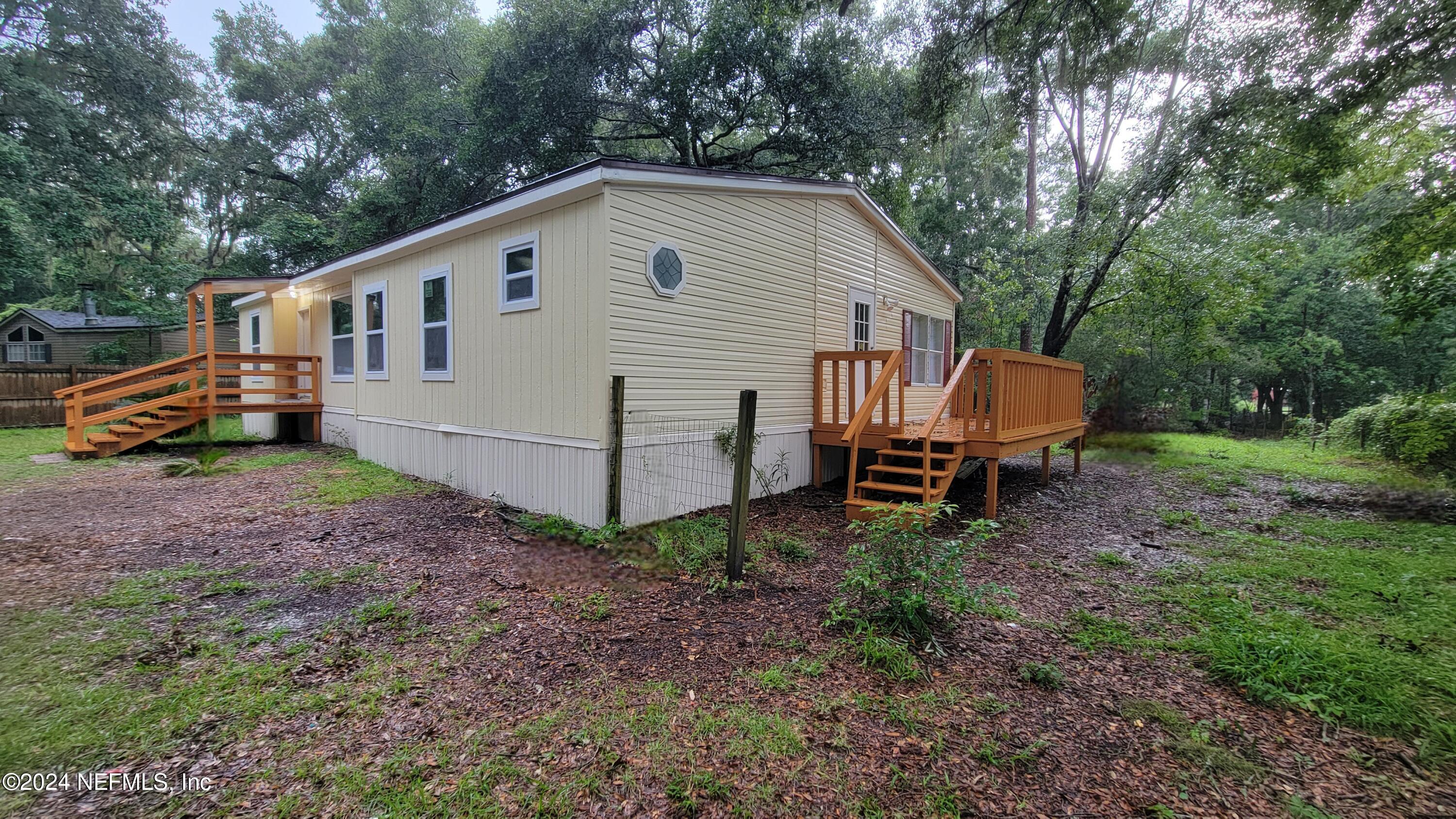 a view of a small house with a yard and fence