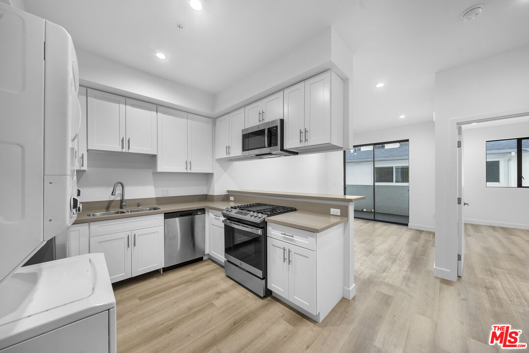 a kitchen with stainless steel appliances granite countertop a stove top oven a sink and white cabinets