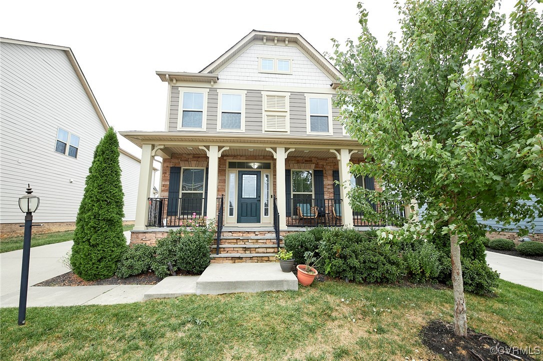 View of front of house with a porch and a front ya