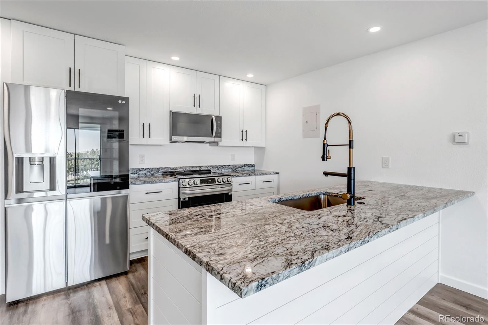 a kitchen with stainless steel appliances granite countertop a sink and a refrigerator