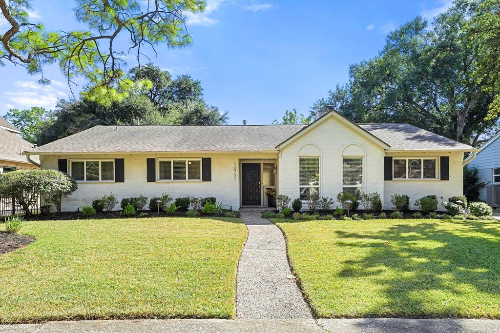 Charming single-story home with well-maintained landscaping, double pane windows, and a welcoming pathway leading to the front door. The property features a large front lawn and mature trees, offering both curb appeal and shade.