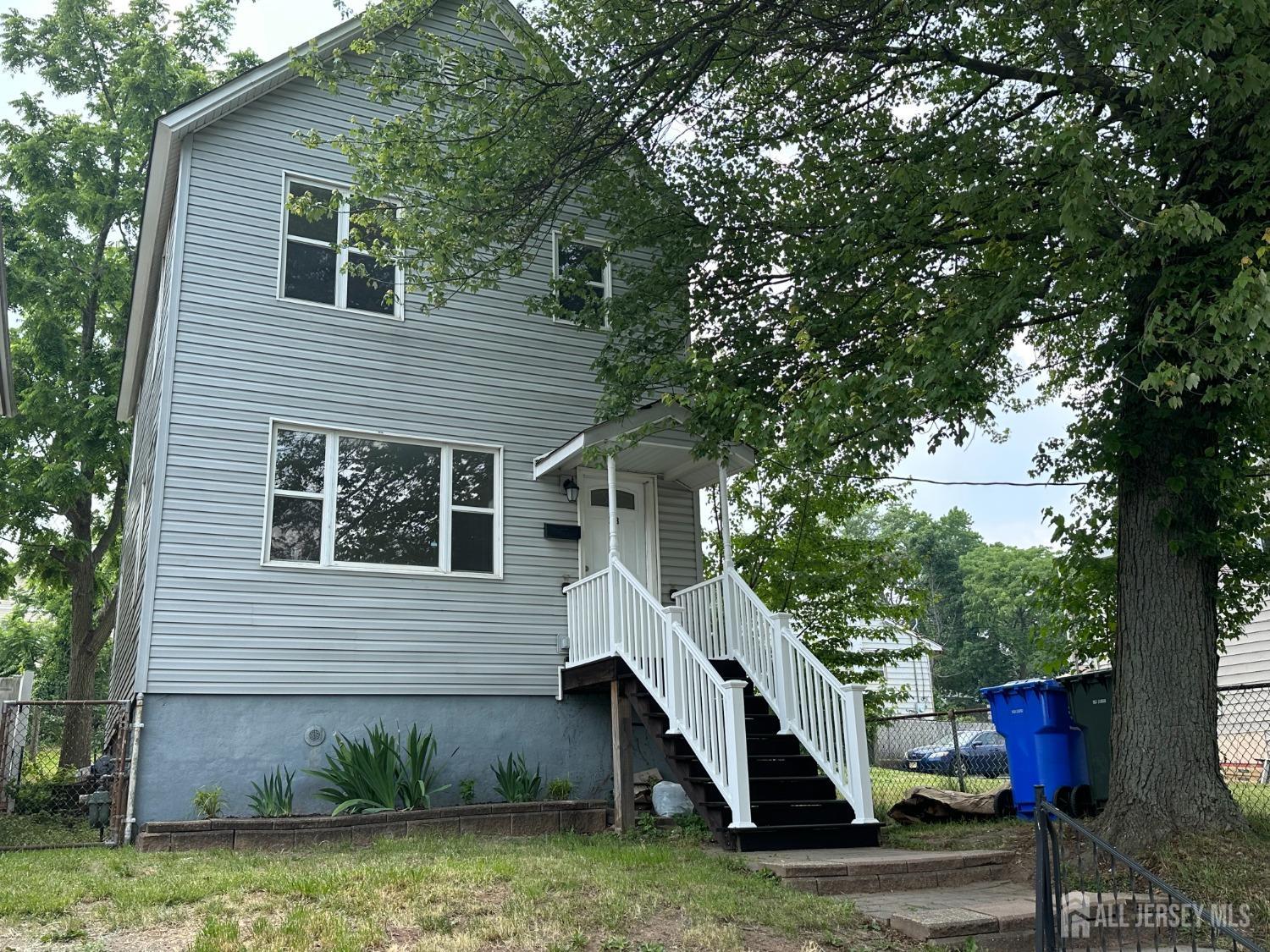 a view of a house with a yard and a large tree