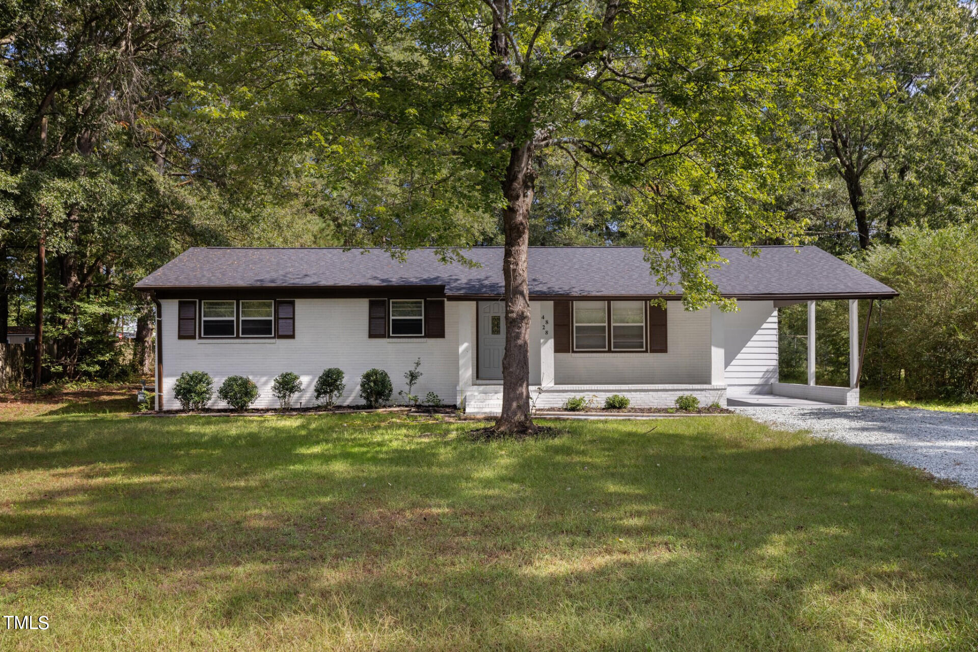 a front view of a house with a garden and trees