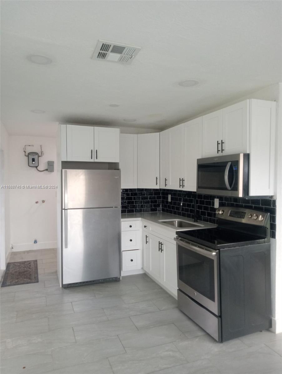 a kitchen with stainless steel appliances white cabinets and a refrigerator