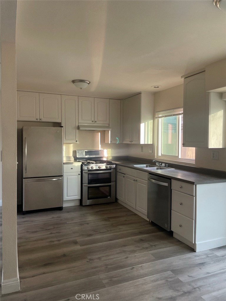 a kitchen with granite countertop a refrigerator stove and wooden floor