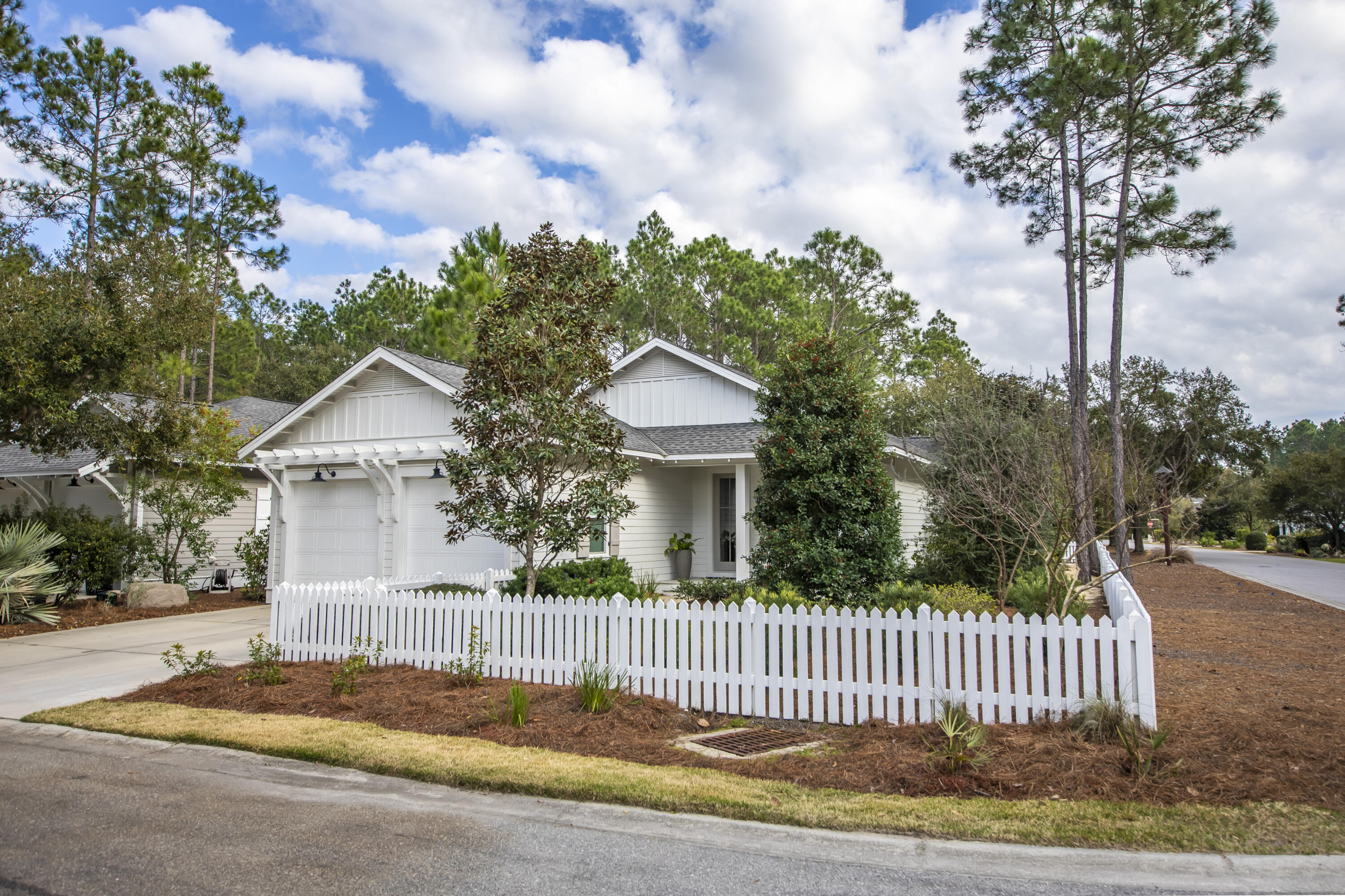 a view of a house with a small yard plants and large trees