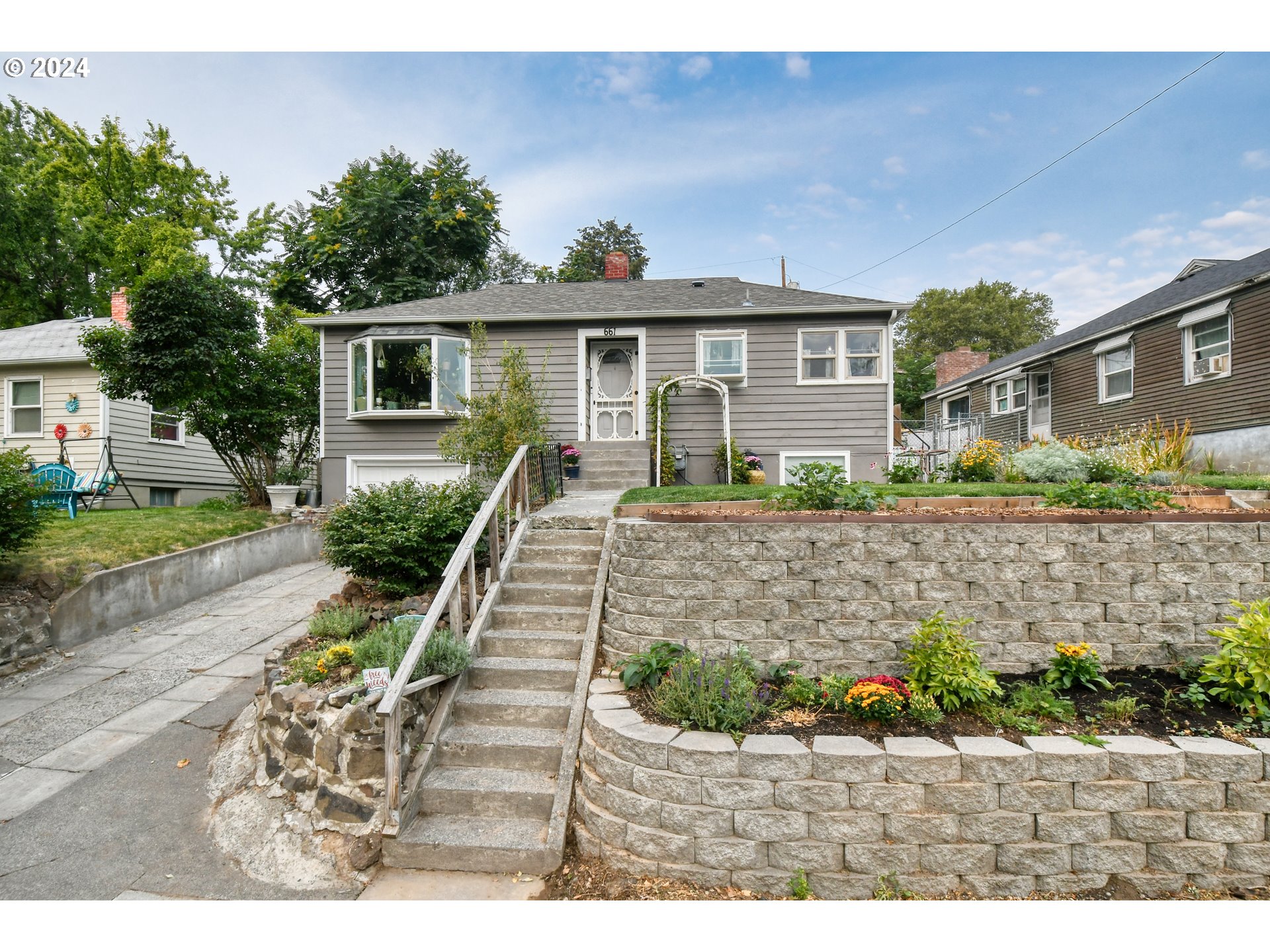 a front view of a house with a yard and potted plants