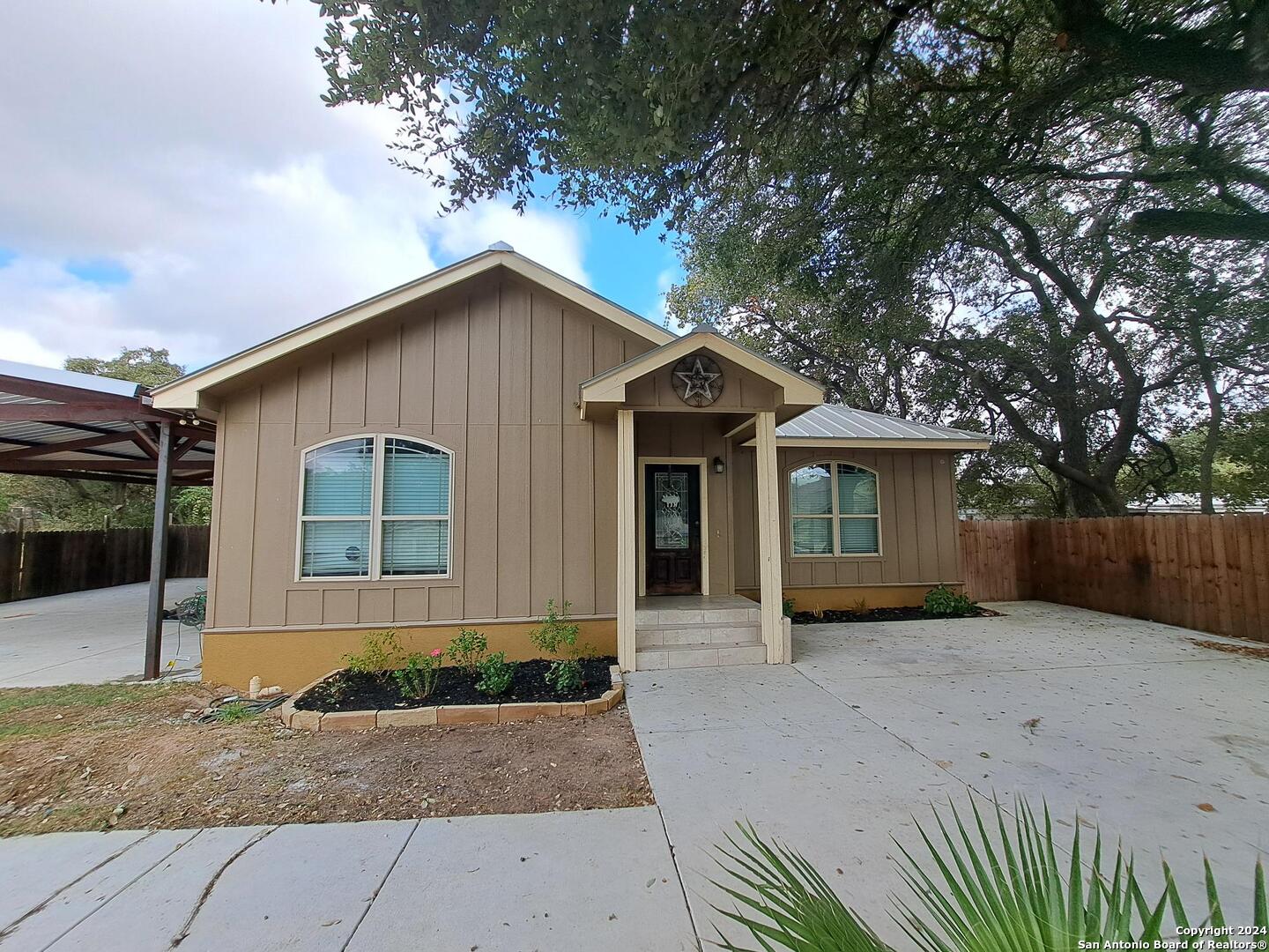 a front view of a house with yard and tree