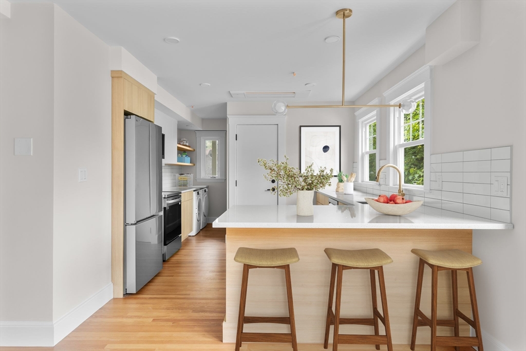 a kitchen with stainless steel appliances a dining table chairs sink and cabinets