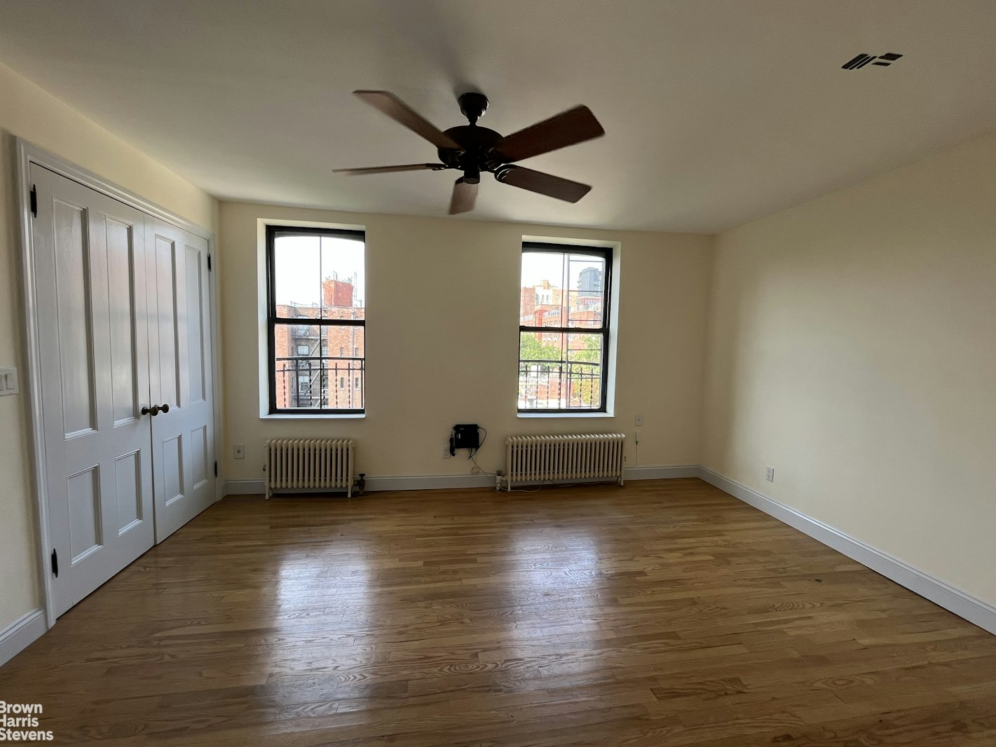 a view of an empty room with a window and wooden floor