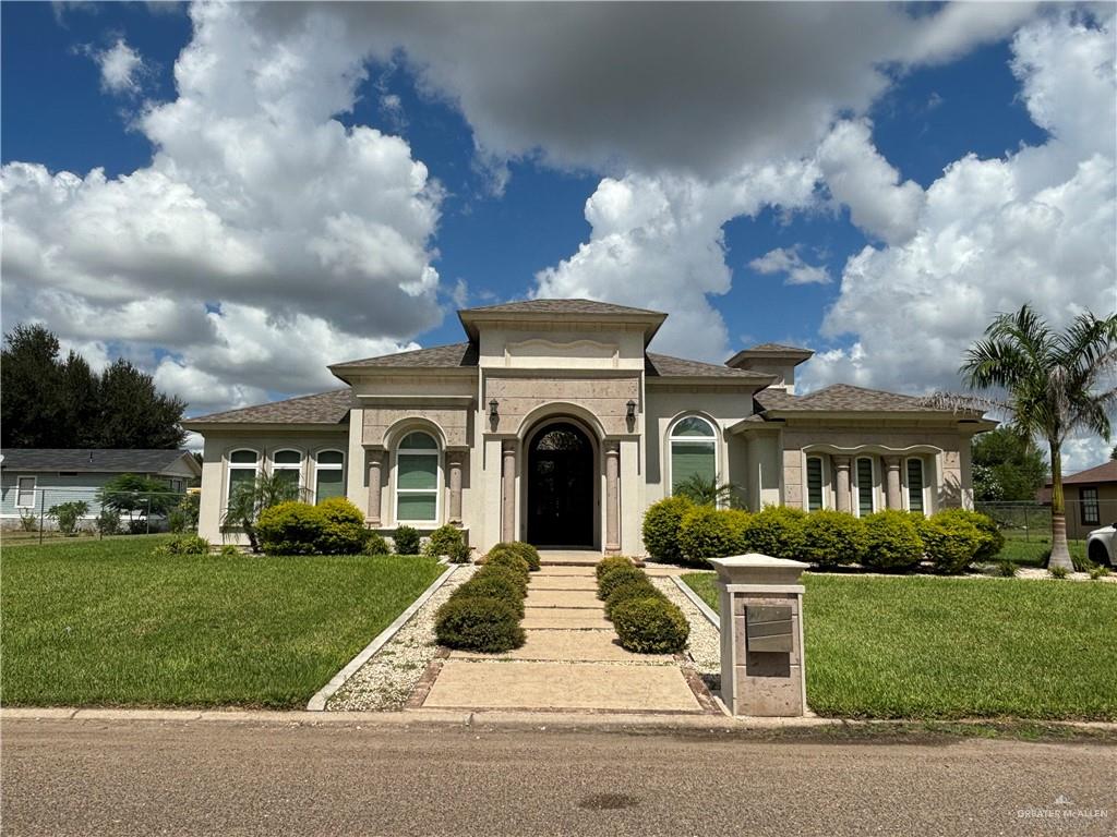 a view of a white house with a big yard and potted plants