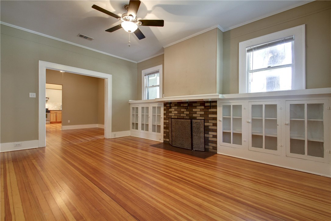 a view of empty room with wooden floor and fan