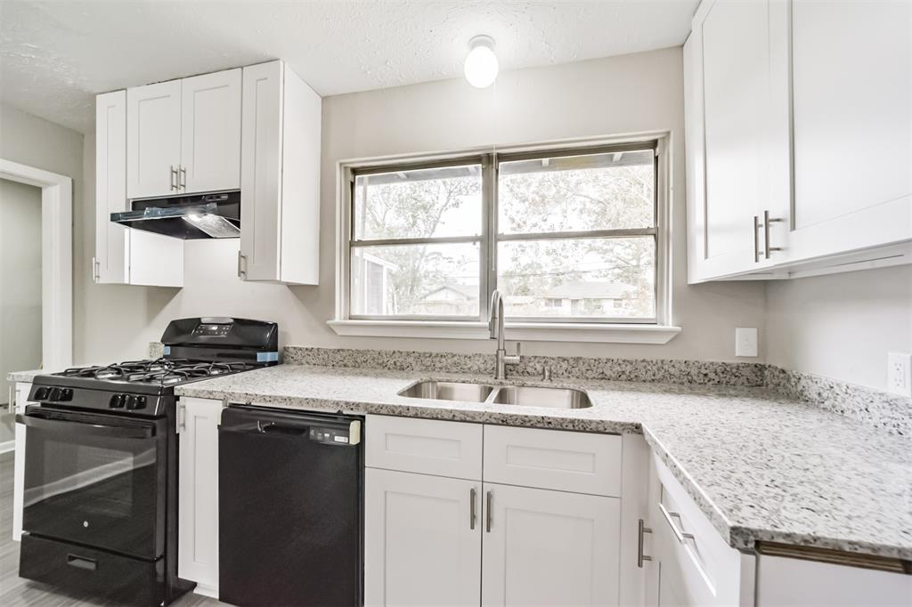 a kitchen with granite countertop a sink stove and cabinets