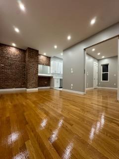 Unfurnished living room with hardwood / wood-style flooring and brick wall