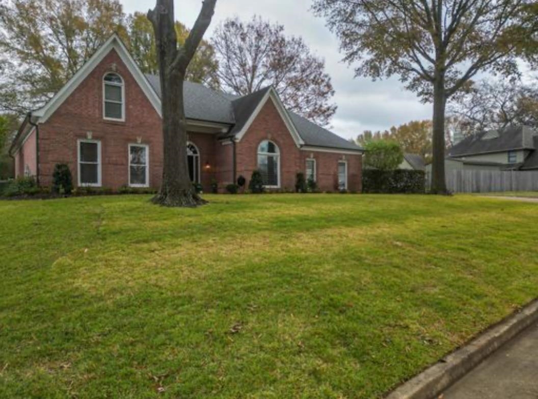 a front view of a house with a yard and trees