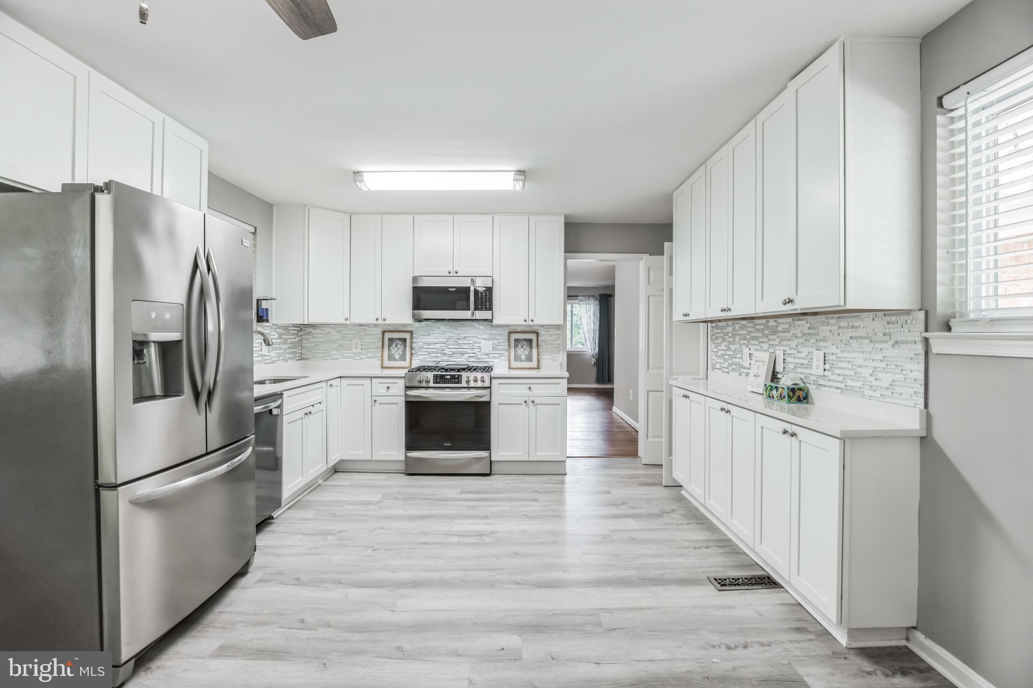 a kitchen with white cabinets stainless steel appliances and window