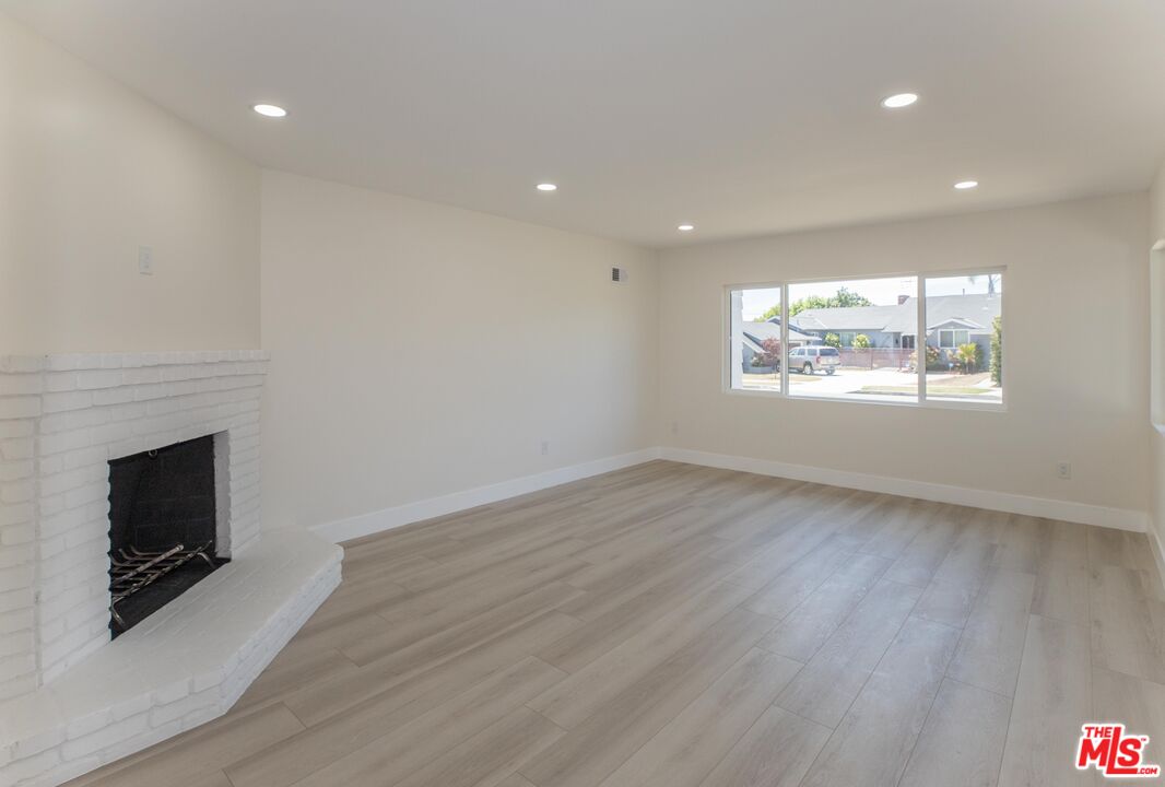 an empty room with wooden floor and fireplace