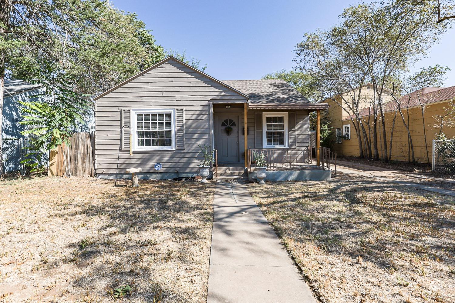 a front view of house with yard and trees in the background