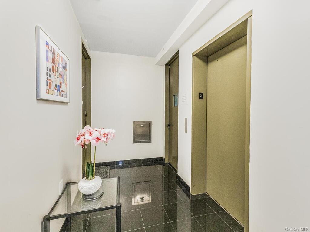 Corridor featuring elevator and dark tile patterned flooring