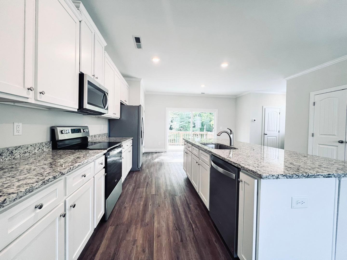 a large kitchen with stainless steel appliances granite countertop a lot of counter space and wooden floors