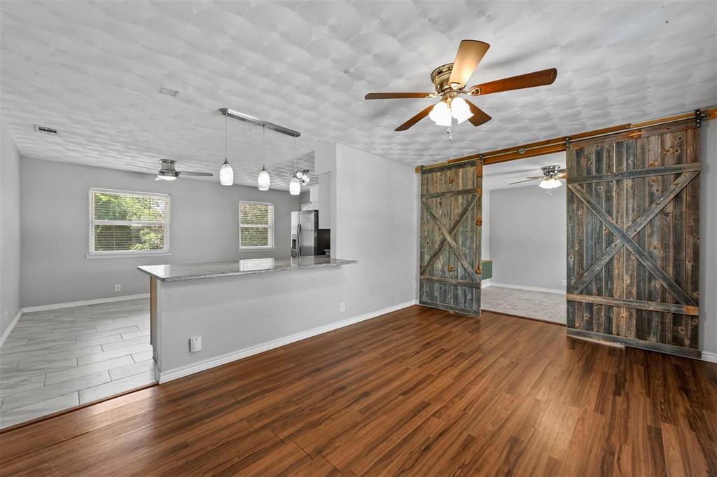 an empty room with wooden floor fan and windows