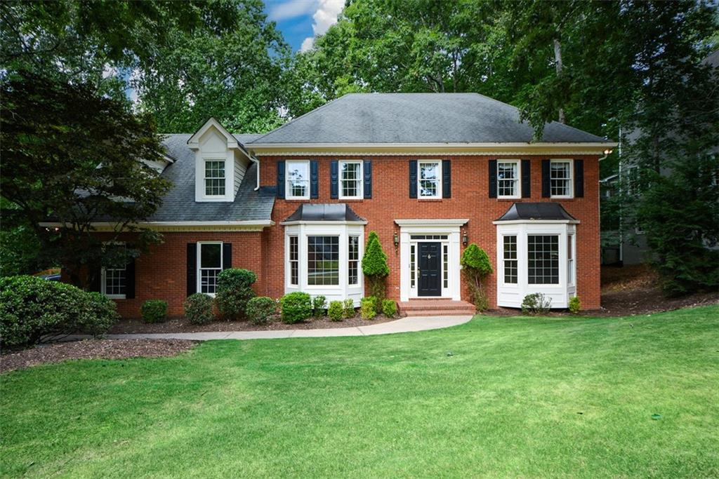 a front view of a house with a yard and trees