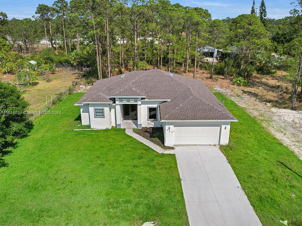 a aerial view of a house next to a big yard and large trees