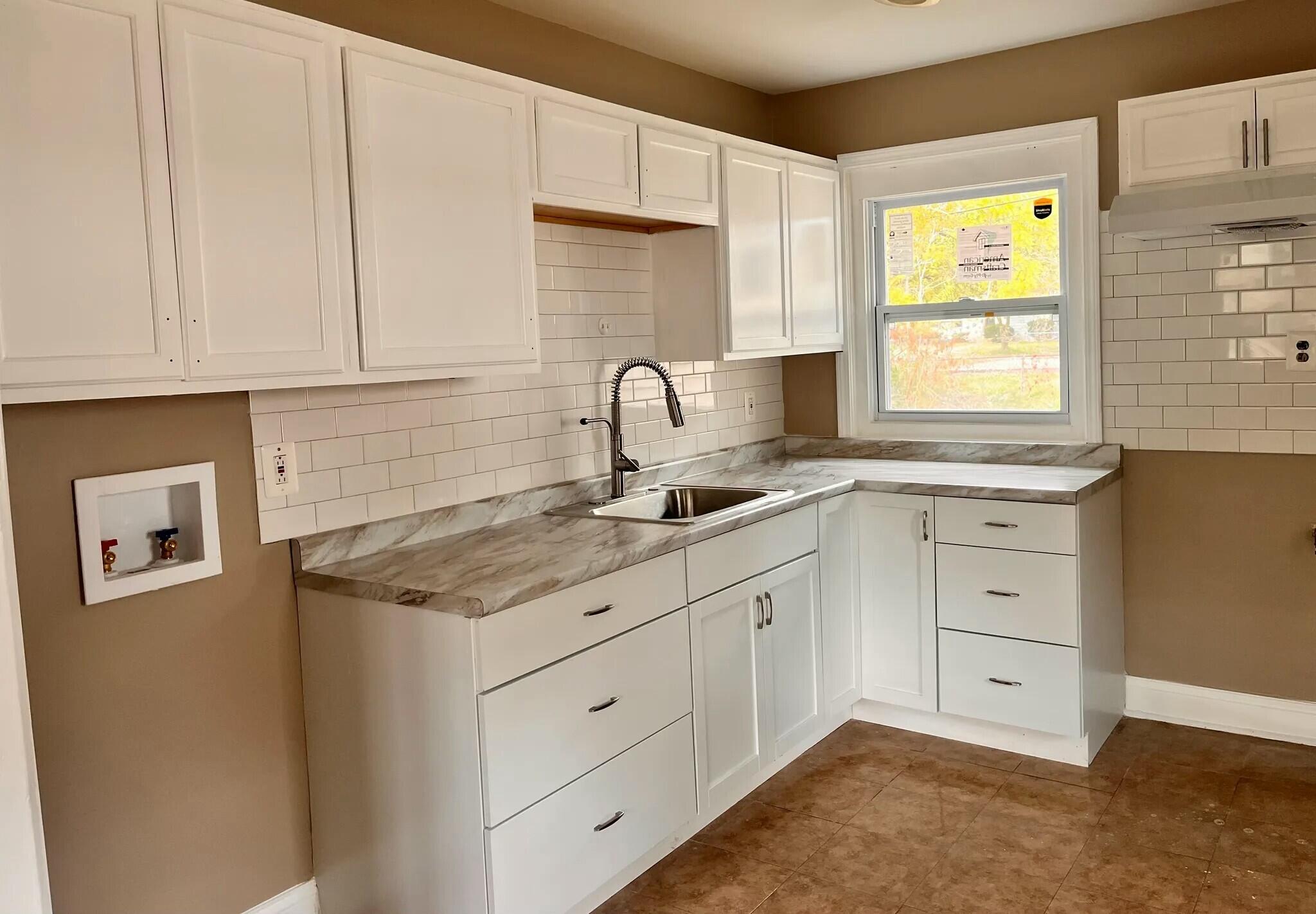 a kitchen with cabinets appliances a sink and a window