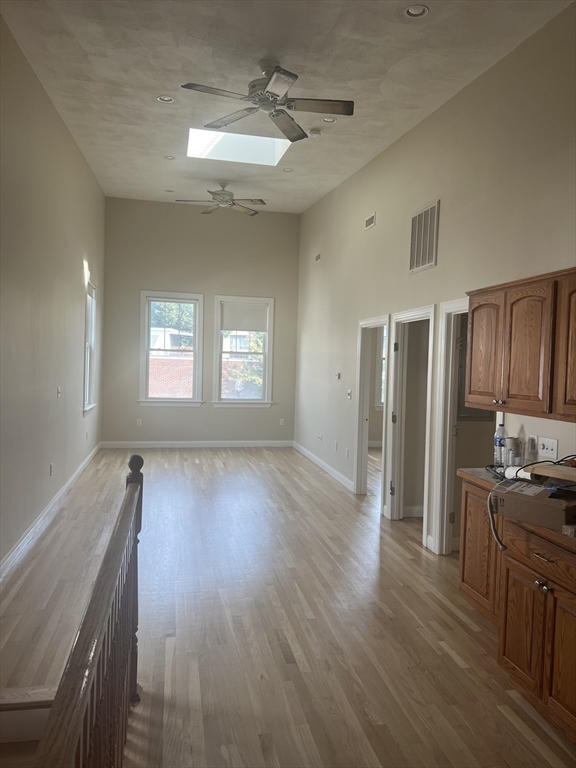 a view of a kitchen and an empty room with wooden floor and a window