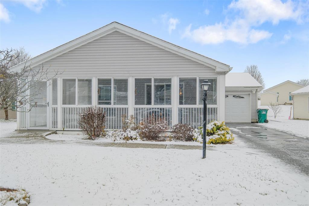 View of front facade featuring a garage and a 3 season porch