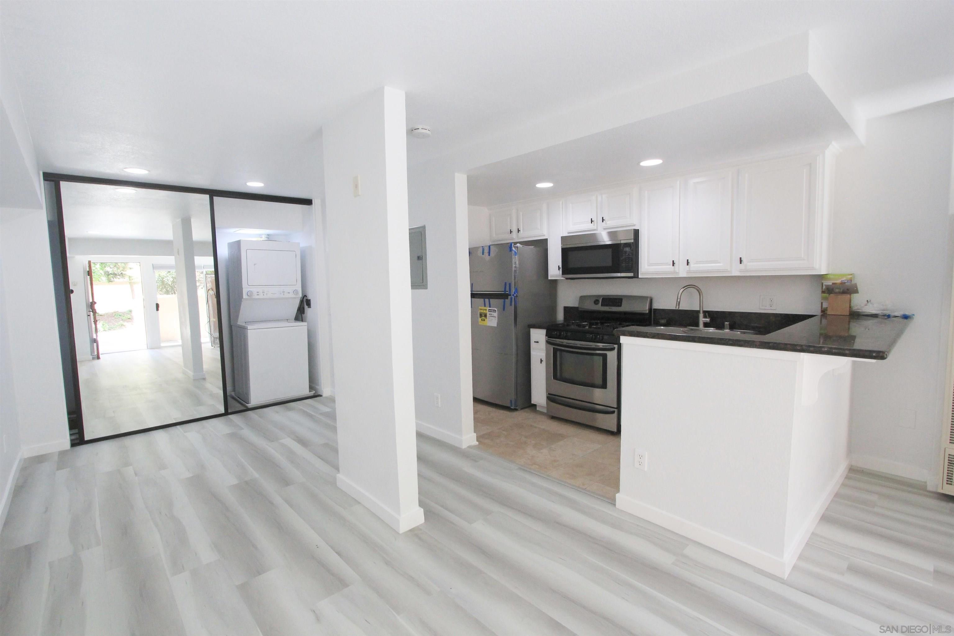 a kitchen with stainless steel appliances granite countertop a refrigerator sink and white cabinets