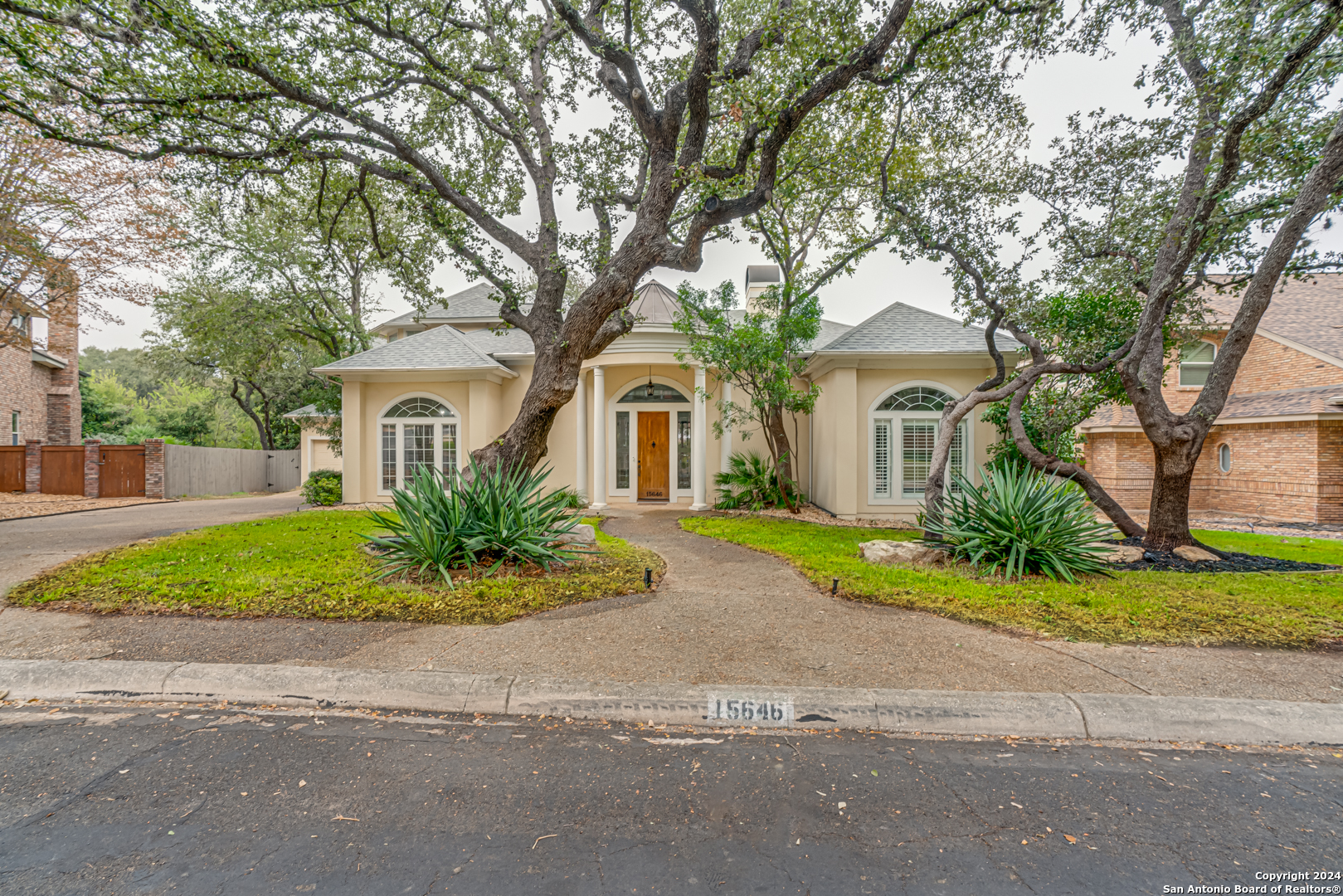 a front view of a house with a garden and trees