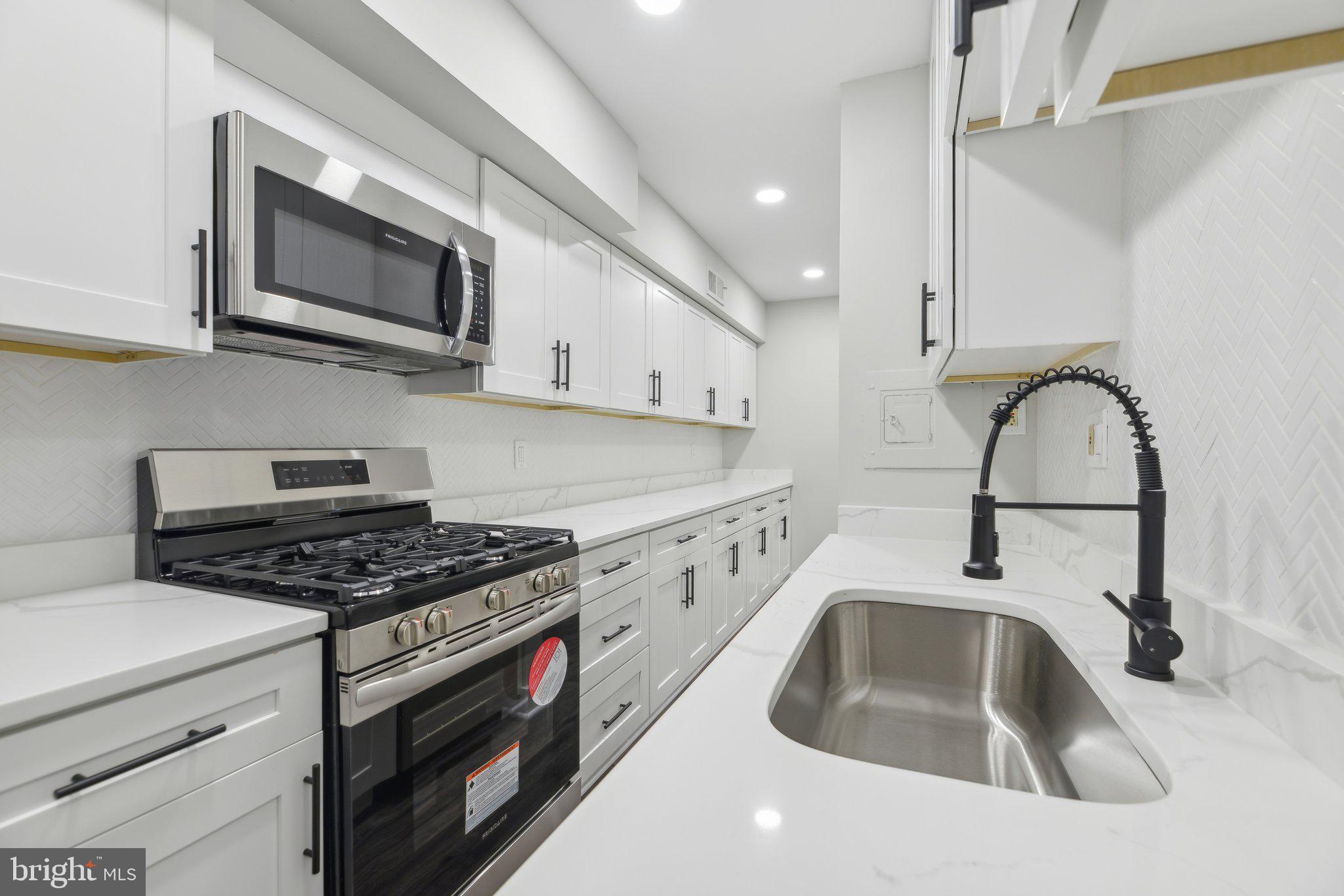 a kitchen with stainless steel appliances a stove a sink and a microwave