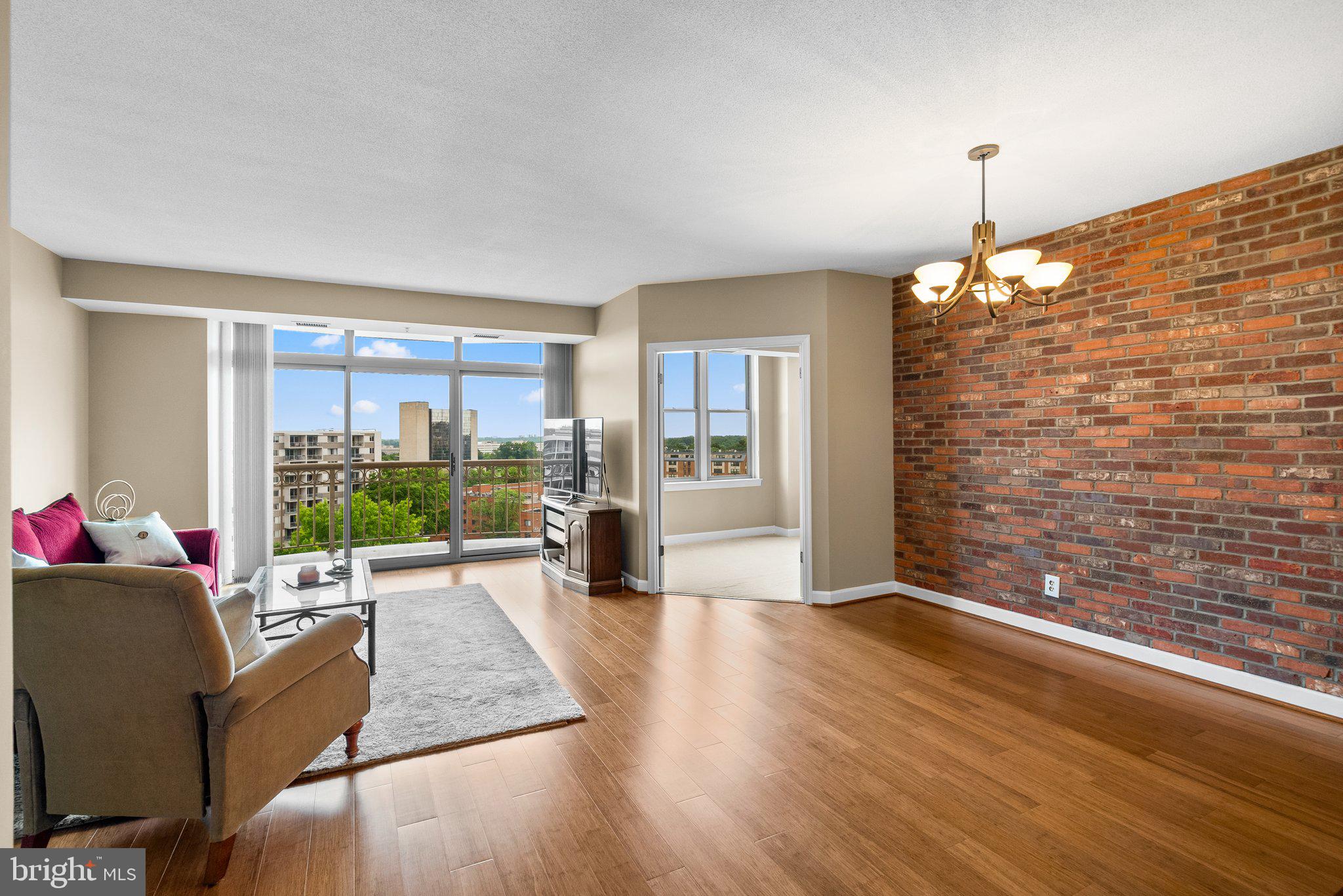 a living room with furniture floor to ceiling window and wooden floor