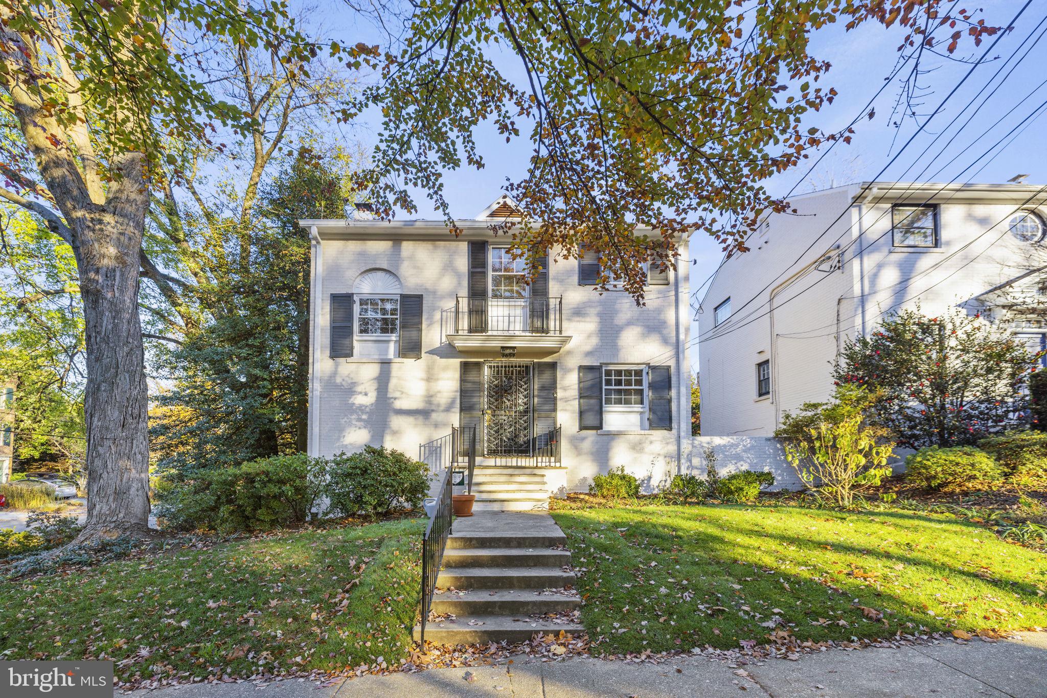 a front view of a house with a garden and trees