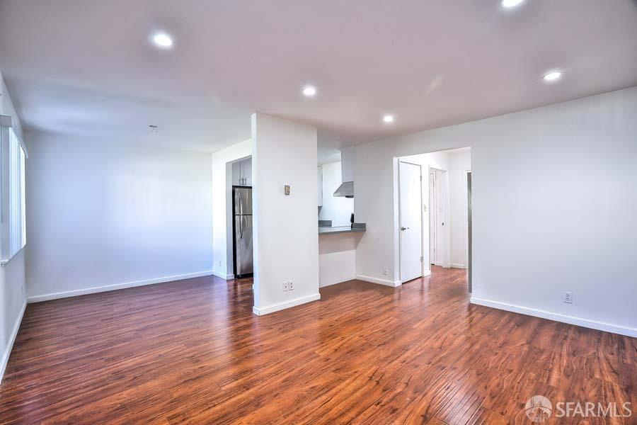 a view of a big room with wooden floor and a kitchen