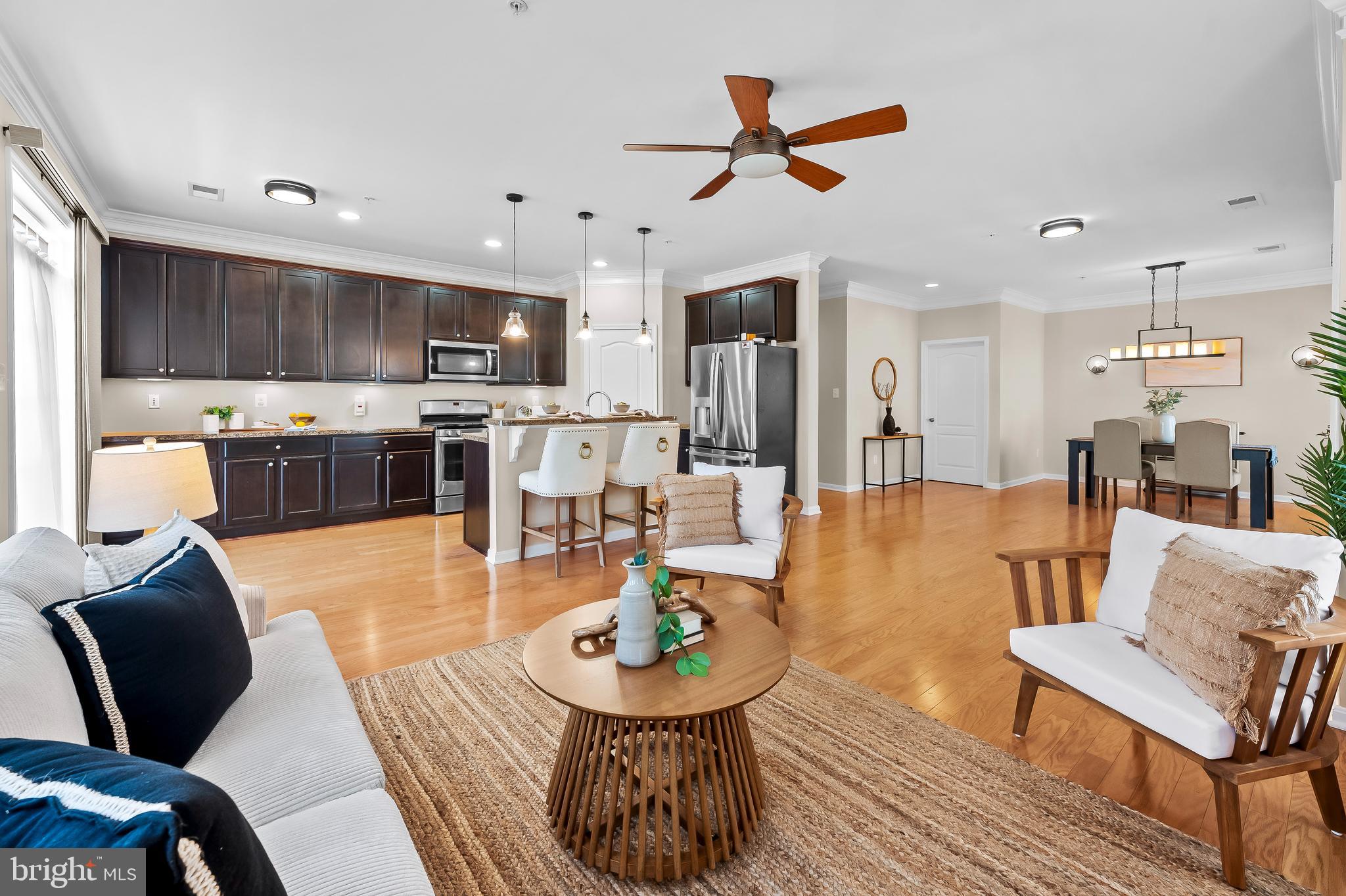 a living room with furniture kitchen view and a wooden floor