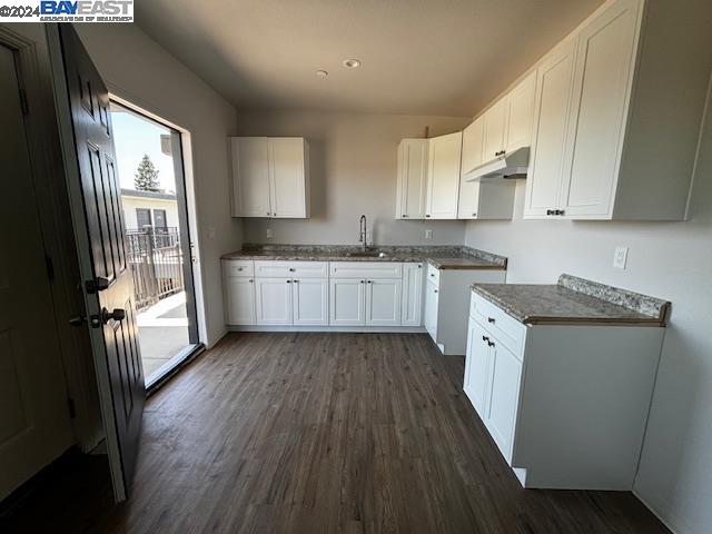 a kitchen with granite countertop wooden floors a sink dishwasher and a stove