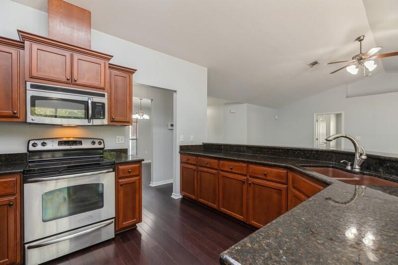 a kitchen with granite countertop wooden cabinets stainless steel appliances and a sink