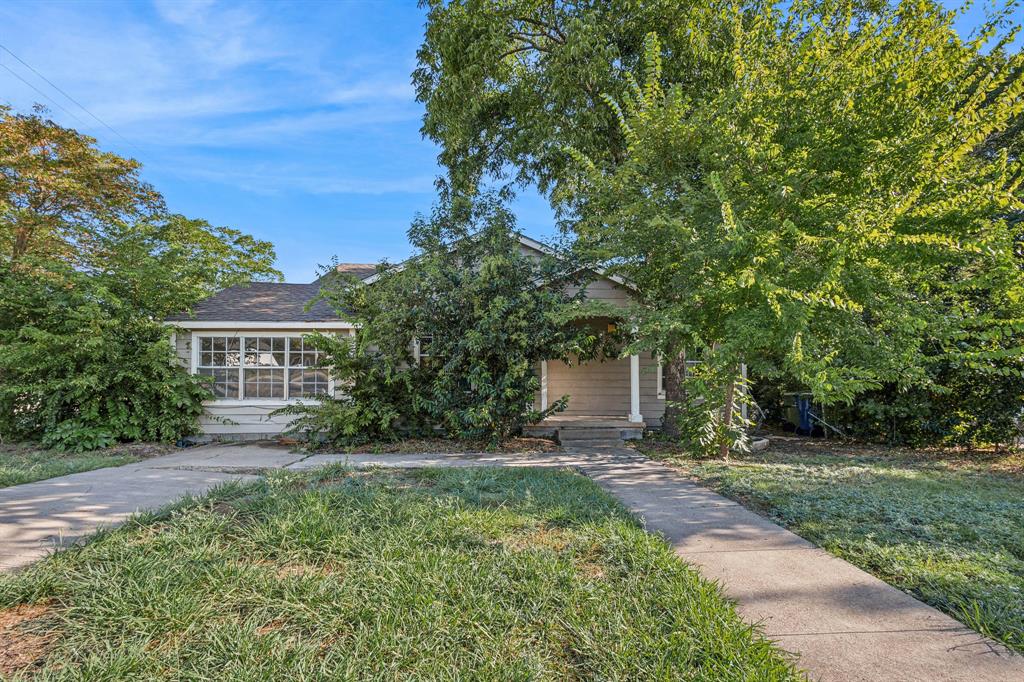 a view of house in front of a big yard with large trees