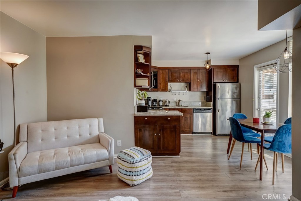 a living room with stainless steel appliances furniture a couch and a kitchen view