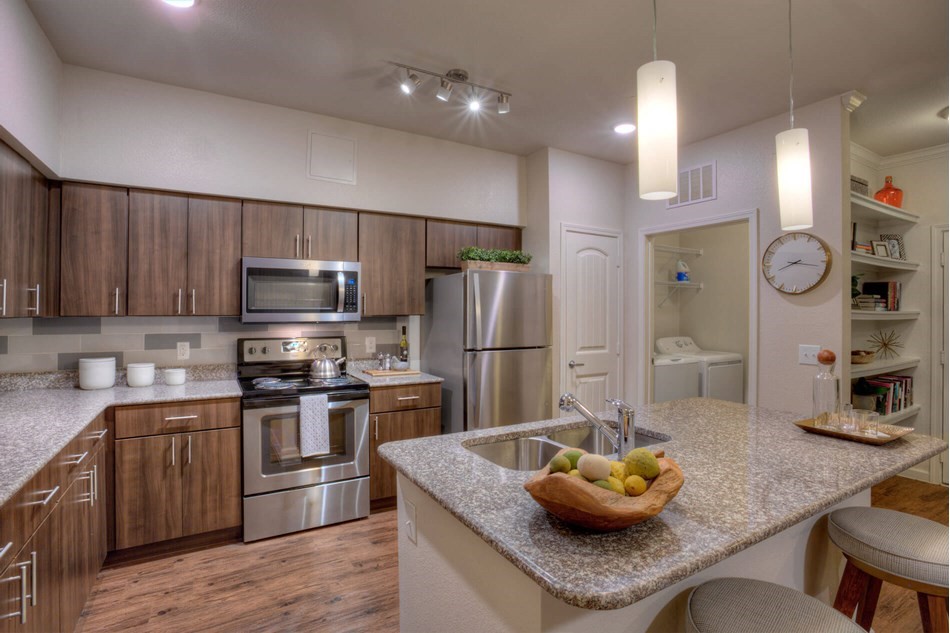 a kitchen with granite countertop a sink cabinets and stainless steel appliances