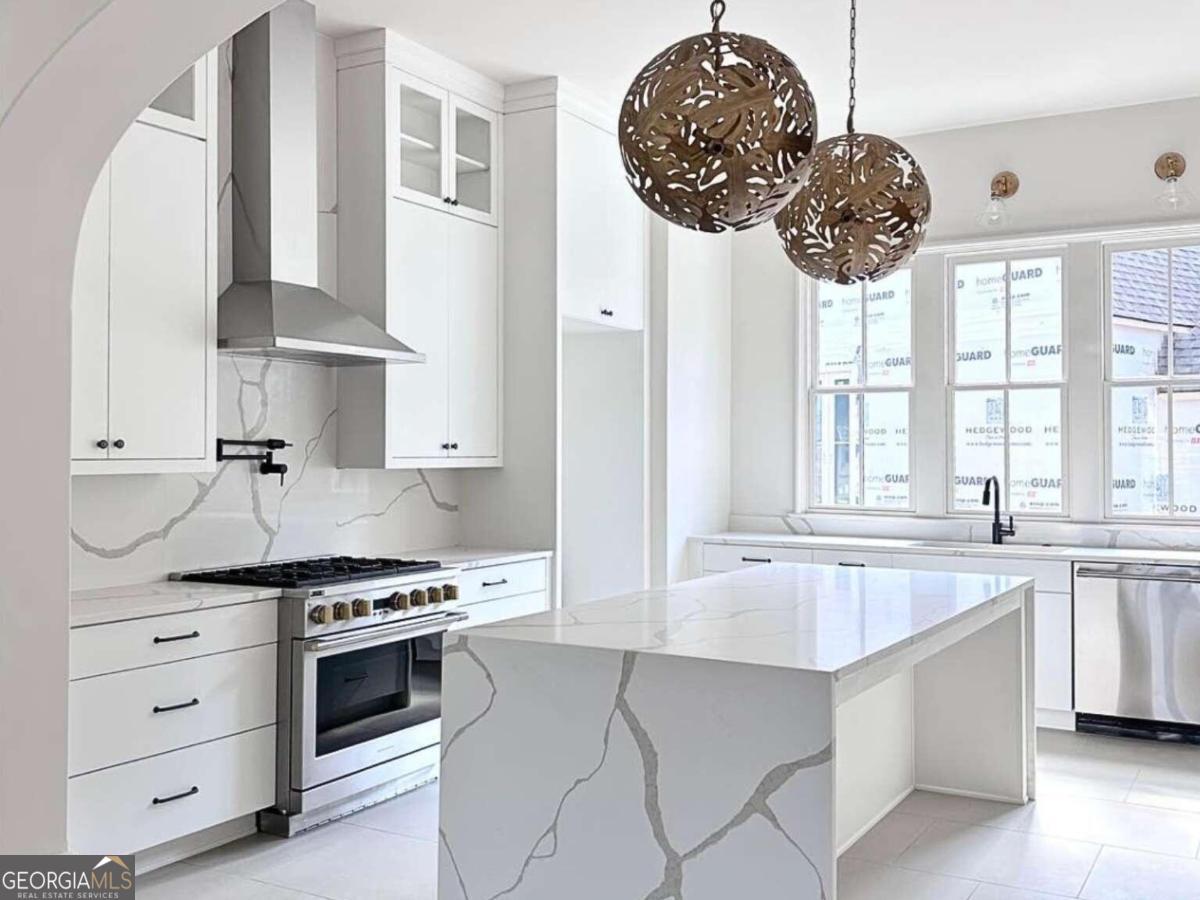 a kitchen with stainless steel appliances a stove a sink and a large window