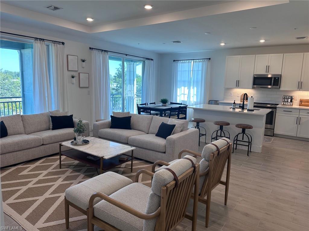 a living room with furniture kitchen view and a window