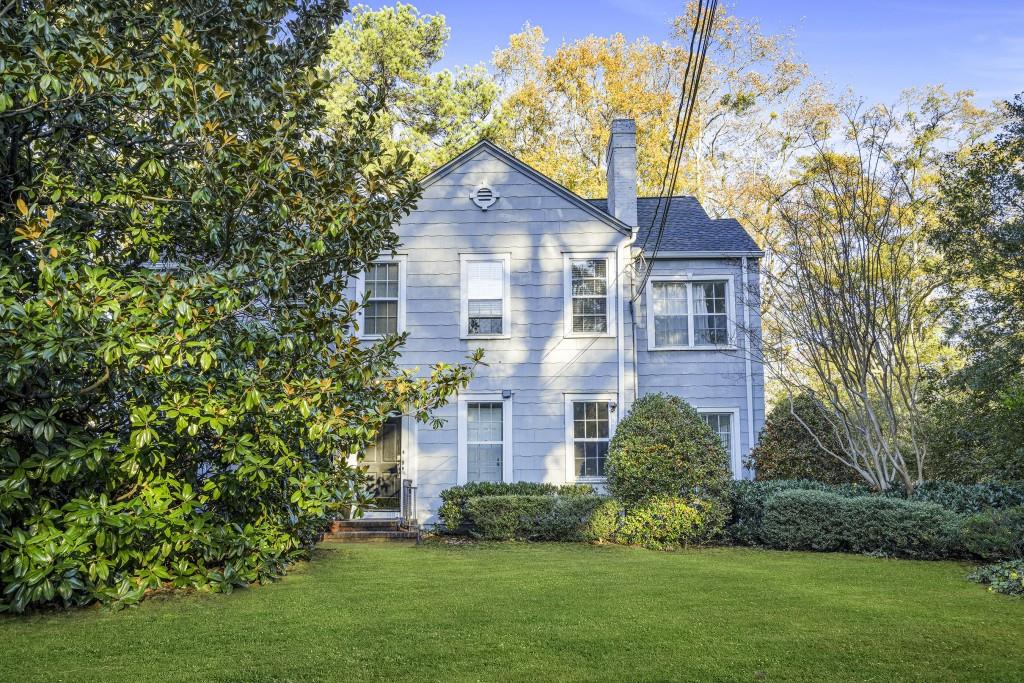 a front view of a house with a yard and trees